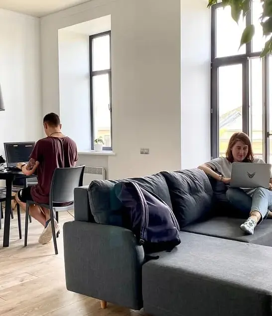 Zwei Chat-Moderatoren beim flexiblen Arbeiten im Homeoffice am Schreibtisch und auf dem Sofa